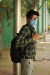 Young Indian middle class young man walking on street and using face mask