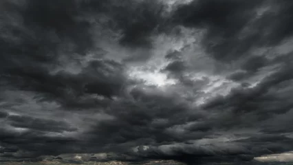 Foto op Plexiglas dark dramatic sky with black stormy clouds before rain or snow as abstract background, extreme weather, the sun shines through the clouds, high contrast photo © soleg