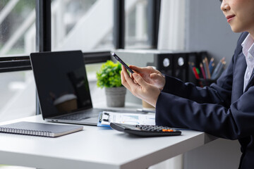 Business asian woman using phone at the office with documents on her desk, doing planning analyzing the financial report, business plan investment, finance analysis concept