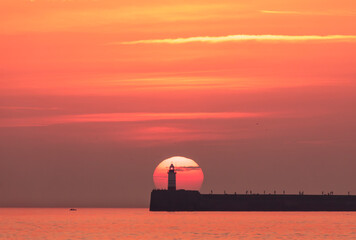 September sunset behind Newhaven lighthouse from Seaford beach on the east Sussex coast south east England UK