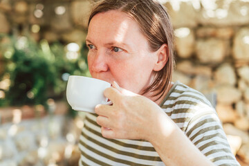 Woman drinking coffee on home terrace in summer morning