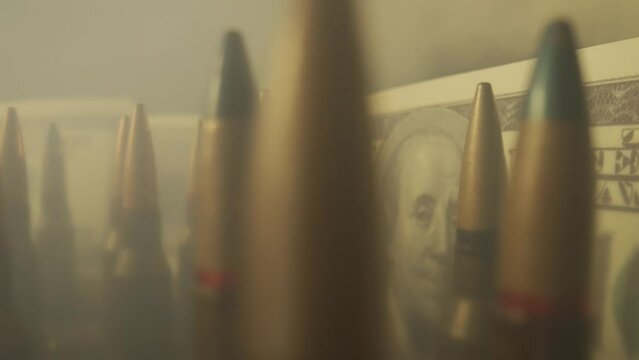 Rifle cartridges on the background of dollar bills in clouds of smoke close up. The concept of the sale of weapons under lendlease, help with weapons, hired work in the army, ammunition trade.