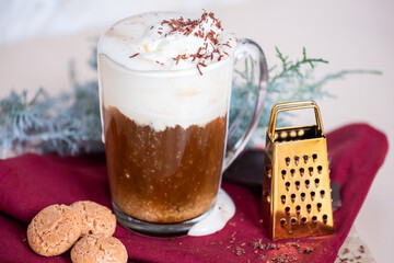 Still life with a cup of coffee latte, cookies and cade branch in Christmas mood. Small gold grater for chocolate. Copy Space