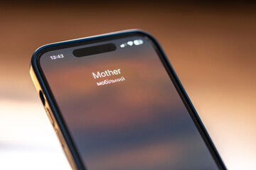 Smartphone in child hands with Incoming Mother call on a screen.