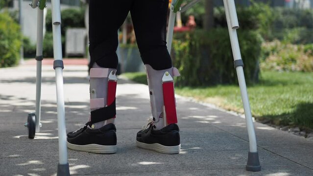  child with walking frame and knee orthosis outdoor 