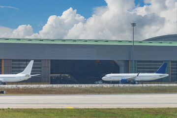 Airport hangar from the outside with big tall doors. Inside passenger planes undergoing maintenance.