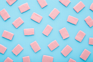 Fototapeta na wymiar Pink sweet chewing gum pads on light blue table. Pattern background. Pastel color. Closeup. Top down view.