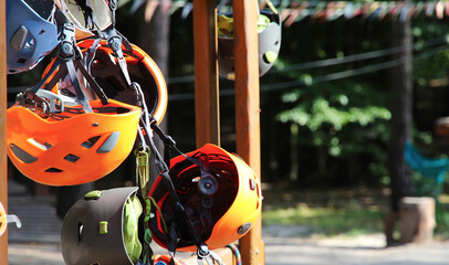 Climbing equipment - colorful helmets hanging on a board in a rope park.