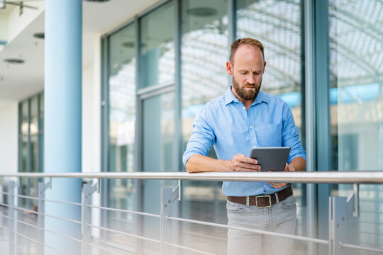 Experienced businessman using digital tablet standing in office building