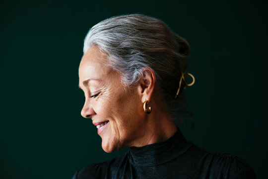 Smiling woman with gray hair in front of wall