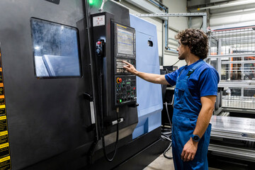 Technician operating and programming metal robotic machinery