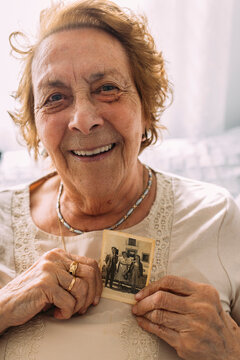 Happy woman holding picture from past on chest