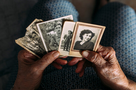 Hands of woman holding photographs from past at home