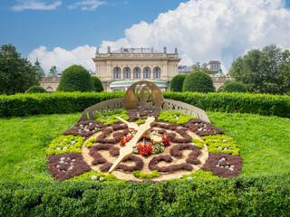 August 5, 2023, Austria, Vienna Clock made of flowers against the backdrop of a music hall Kursalon Hubner in a city park Stadtpark.