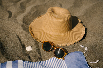 Sun hat next to sunglasses on sand at beach