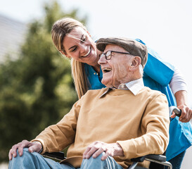 Happy healthcare worker talking with elderly man with disabilities