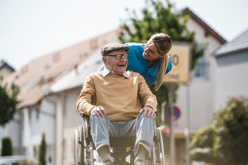 Cheerful nurse talking with senior man sitting in wheelchair