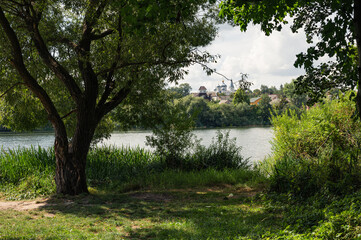 Bank of river with lush green tree, grass and view on orthodox church. Scenic, beautiful, background, postcard view, wallpaper, Vinnytsia, Ukraine, Pivdennyi Buh