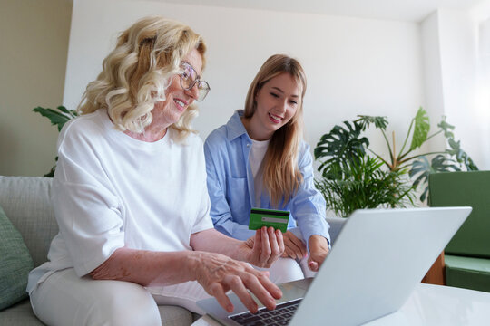 Happy mother and daughter shopping with credit card on laptop at home