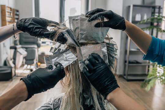 Hairdressers dyeing customer's hair in salon
