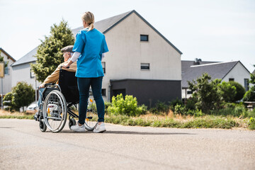 Healthcare worker pushing elderly man sitting in wheelchair