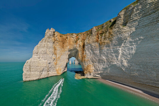 White chalk cliffs with natural arch under sky on sunny day