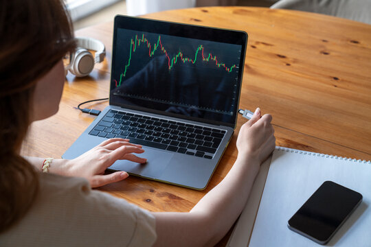 Businesswoman analyzing investment trading data on laptop at home