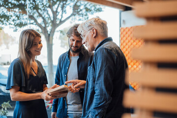 Happy businesswoman showing design model to businessmen in office