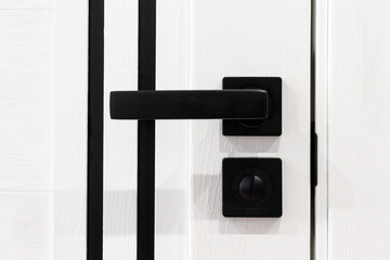Stylish black handle on a white door. Modern trends in interior design. Close-up.