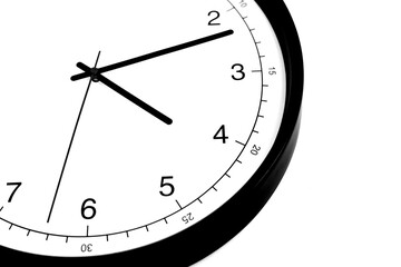 Part of analogue plain wall clock on white wall background. Four o'clock twelve minutes. Close up...