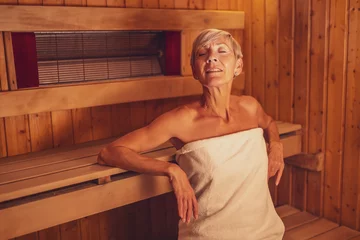 Foto auf Acrylglas Spa Mature woman is relaxing in sauna. Healthy lifestyle for elderly people. Spa concept.