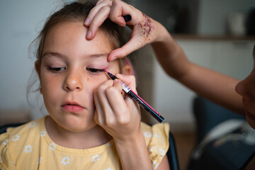 Close-up of makeup artist doing kids makeup with pink eyeliner. Small girl party or birthday day preparation. 