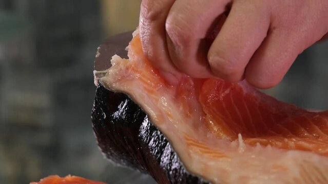 process of salting red fish salmon peel the fish from the husk cover it with Salt and leave it for salting for a while delicious Healthy food natural product seafood female hands close-up. clean fish