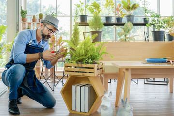 A senior man or grandfather with a mustache enjoys gardening for the tree at home after retirement