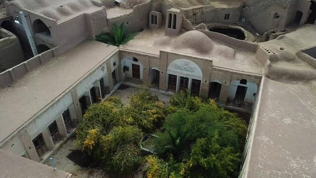 Big beautiful desert house with design and decoration has lots of old ancient wooden door green pomegranate tree and adobe material to make clay house in hot climate
concept of eco lodge resort iran