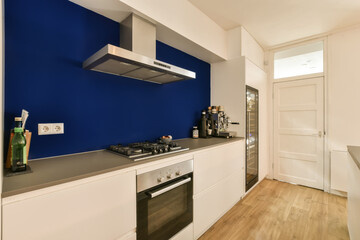 a kitchen area with blue walls and white cupboards on either side, there is an oven in the corner