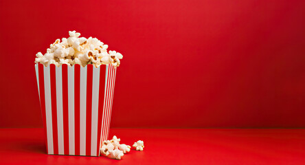 Red and white popcorn box on a red backdrop. Generative AI