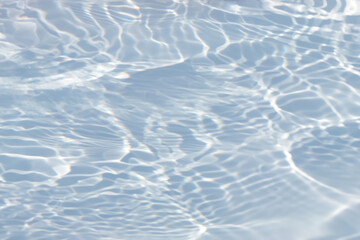 Blue water with ripples on the surface. Defocus blurred transparent blue colored clear calm water surface texture with splashes and bubbles. Water waves with shining pattern texture background.