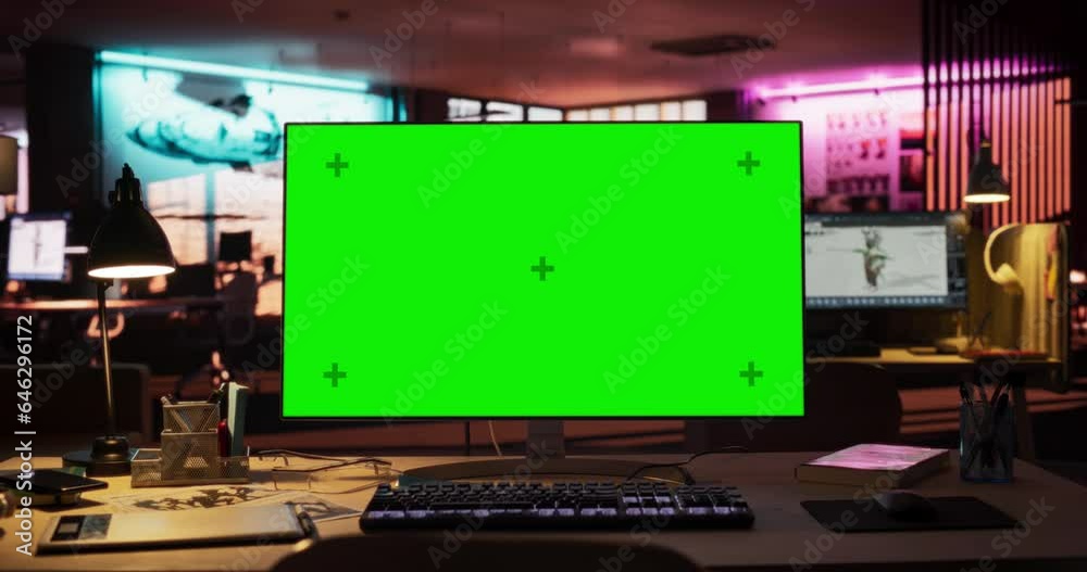 Poster Office Space with Digital Green Screen Mock Up Chroma Key Monitor Standing at Night on Developer's Table. Empty Office of Creative Agency with Art on Walls and Desks with Computers