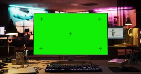 Desktop Computer with Mock Up Green Screen Chroma Key Display Standing on the Desk in the Empty Creative Office Lit by Neon Lights. Monitor in Game Development or Animation Company. Zoom Out