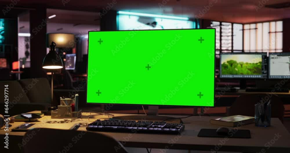 Poster Empty Office of Creative Agency with Art on Walls and Desks with Computers. Office Space with Digital Green Screen Mock Up Chroma Key Monitor Standing at Night on Developer's Table