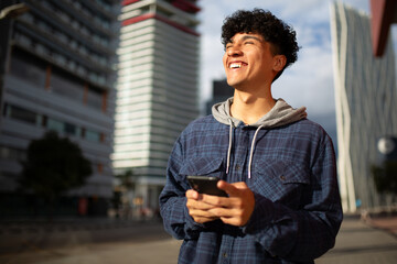 happy young man holding cellphone in city