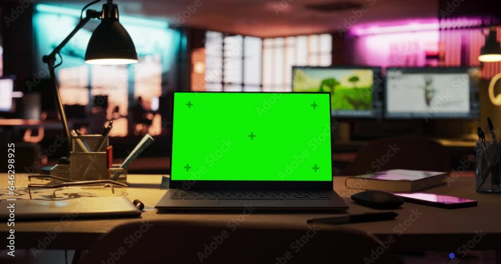 Poster zoom out shot of laptop computer standing on a wooden desk with a green screen chromakey mock up dis
