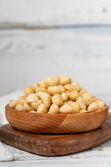Macadamia nut in wood bowl. Macadamia nuts peeled on white wood background. Close up