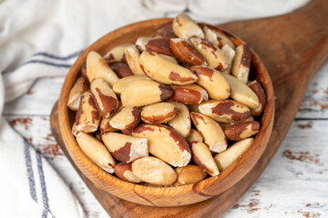 Brazil nut in wood bowl. Brazilian nuts peeled on white wood background