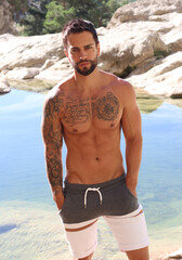 Handsome shirtless fitness man in front of water