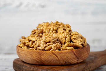 Walnut in wood bowl. Walnut peeled on white wood background. Close up