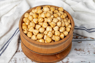 Roasted hazelnuts in wood bowl. Peeled hazelnuts kernel on white wood background. Close up