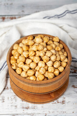 Roasted hazelnuts in wood bowl. Peeled hazelnuts kernel on white wood background