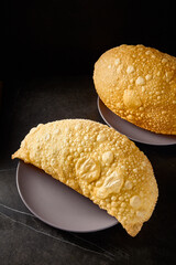 A gigantic cheburek filled with meat, showcased on a black marble table, a modern take on Uzbek cuisine